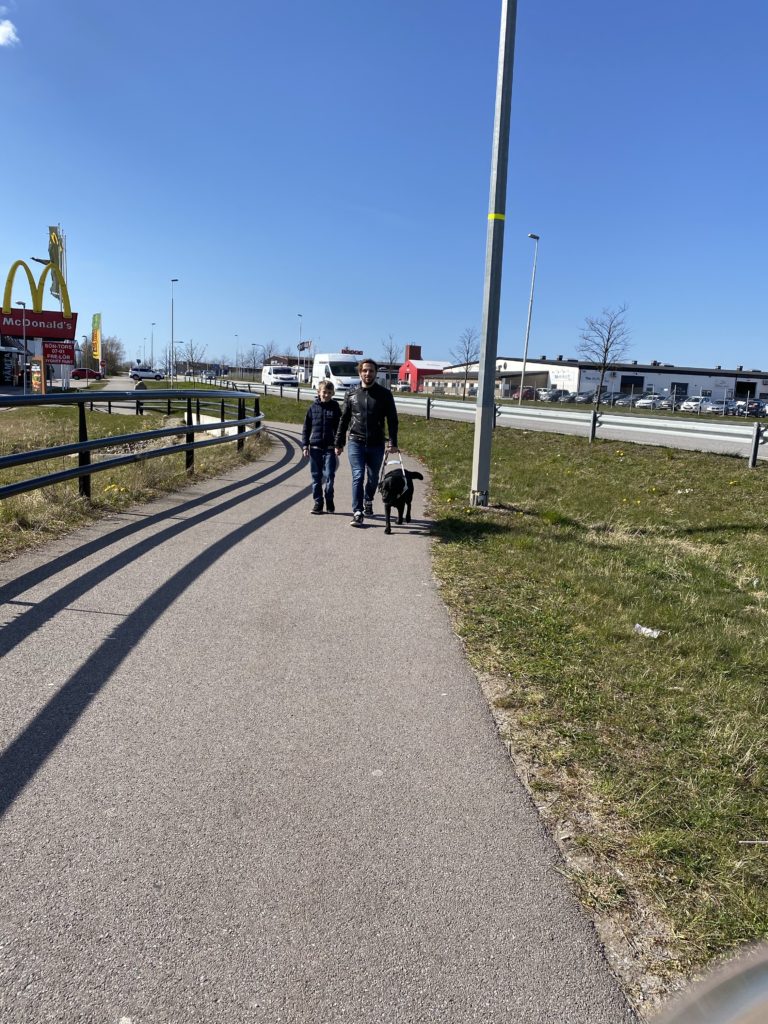 Fatmir Seremeti går på en gång och cykelbana med sin ledarhund Gibson till vänster om sig och sin son Adrian till höger. 